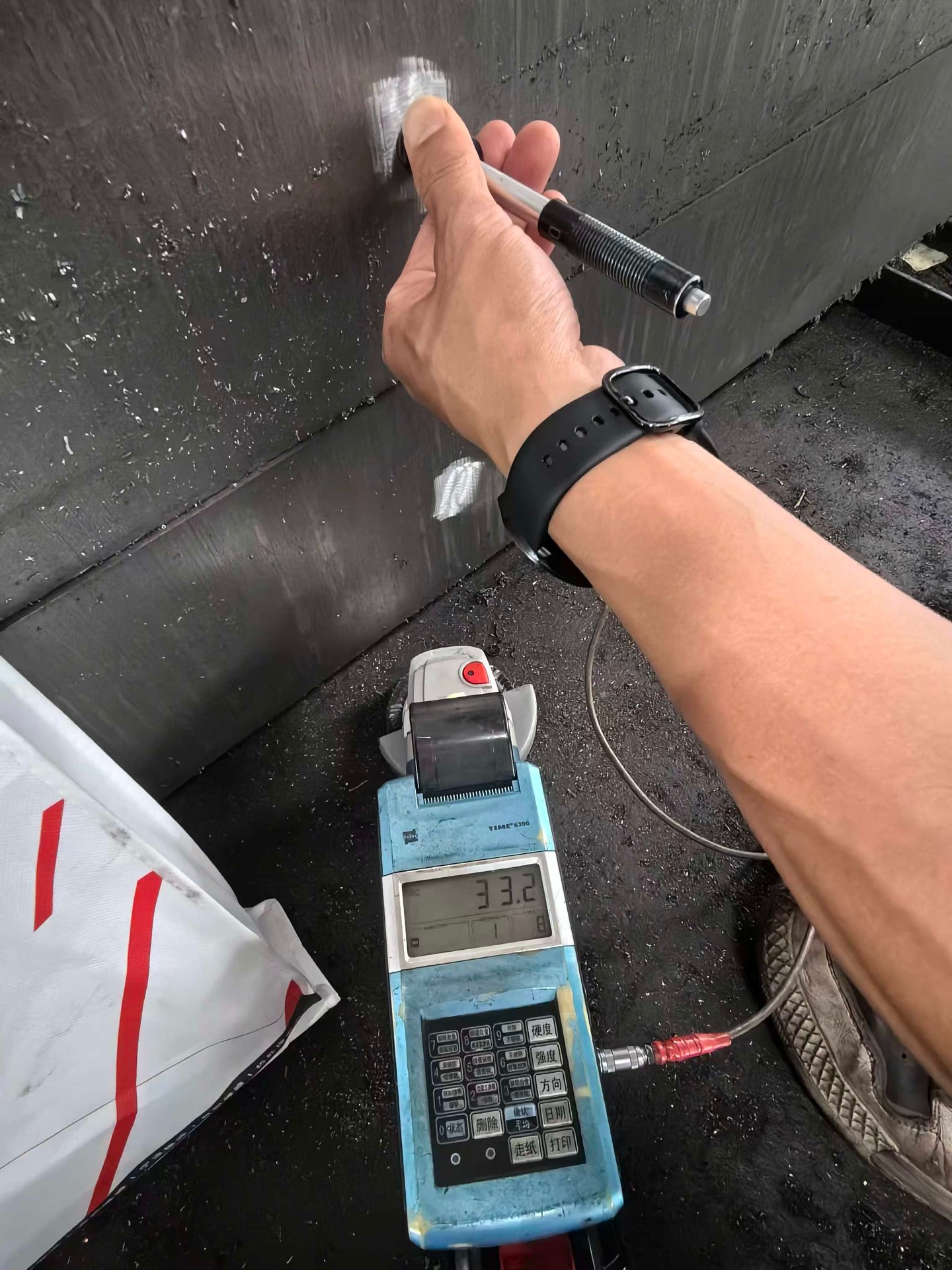Portable hardness tester reading HRC on steel plate